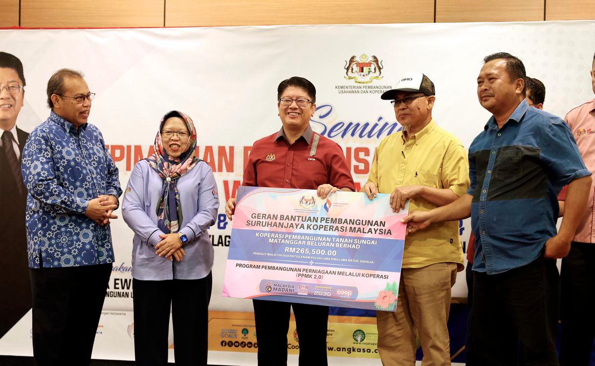 Menteri Pembangunan Usahawan dan Koperasi Datuk Ewon Benedick (tengah) menyampaikan Geran Bantuan Pembangunan Suruhanjaya Koperasi Malaysia kepada wakil Koperasi Pembangunan Tanah Sungai Matanggar Beluran Berhad bernilai RM265,500 pada Majlis Penutupan Seminar Kepimpinan dan Keusahawanan Koperasi Wanita Sabah hari ini. - BERNAMA