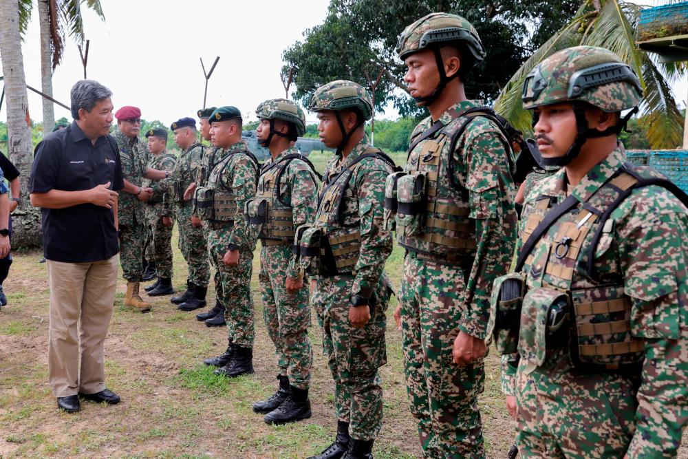 LAHAD DATU, 10 Feb -- Menteri Pertahanan Datuk Seri Mohamad Hasan (kiri) beramah mesra dengan sebahagian anggota keselamatan yang bertugas ketika mengadakan lawatan kerja di Pos Kampung Tanduo hari ini. fotoBERNAMA