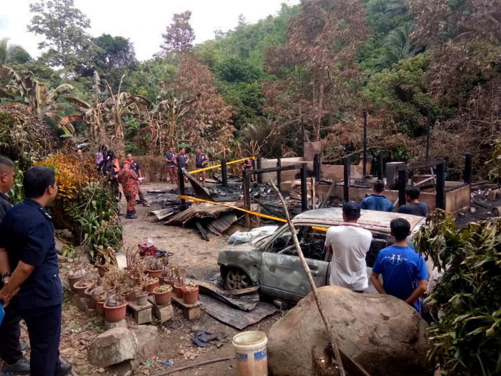 Officers from the Fire and Rescue Department examine the site where five members of a family perished in a fire at a house in Kampung Menara Pamilaan, Tenom, on Dec 31, 2019. — Bernama