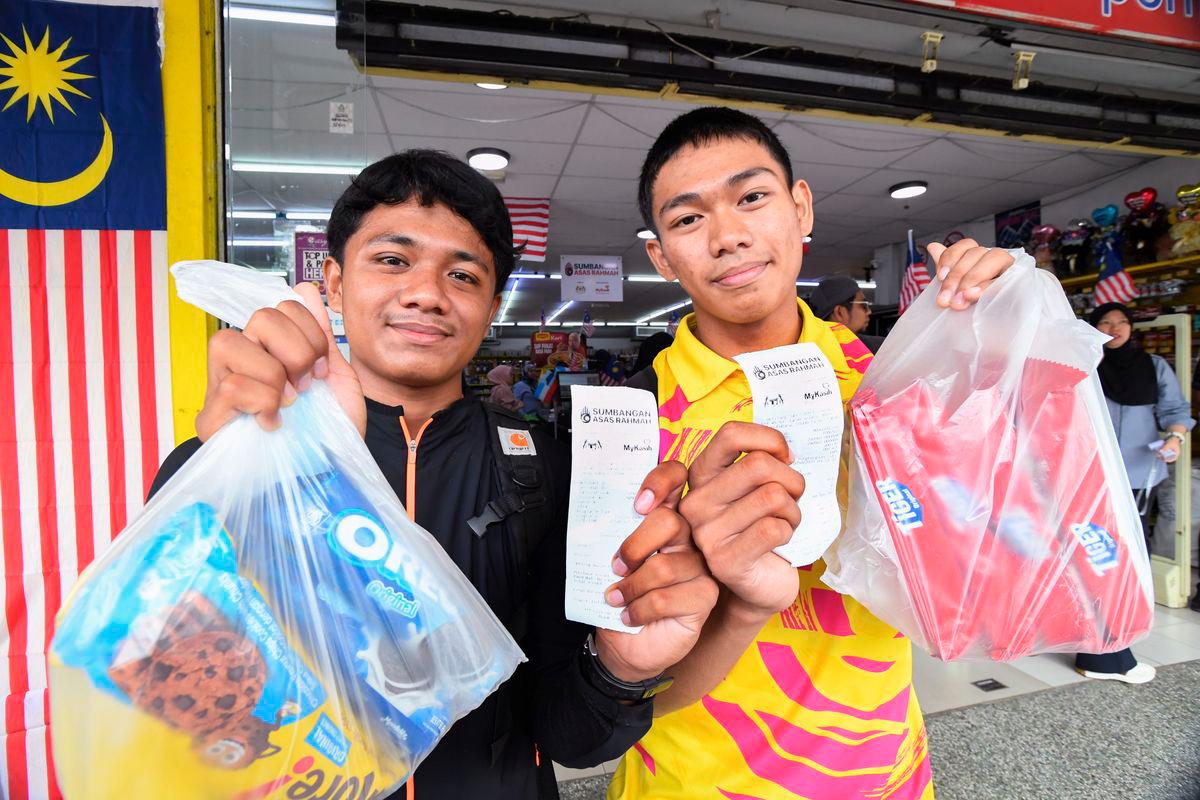 Pelajar Kolej Tingkatan Enam Mohd Fitri Fawwaz Abdul Fattah, 18, (kiri) dan pelajar Kolej Vokasional Anas Mohammad, 18, menunjukkan resit pembelian barangan keperluan menggunakan bantuan Sumbangan Asas Rahmah (SARA) bernilai RM100 di sebuah pasaraya di Merotai hari ini - fotoBERNAMA