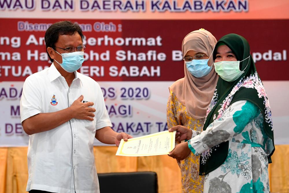 Sabah Chief Minister Datuk Seri Mohd Shafie Apdal participates in the handing over ceremony of 67 new houses and 308 land titles to fire victims in Kampung Tanjung Batu Otentik and land title in Tawau and Kalabakan today. - Bernama