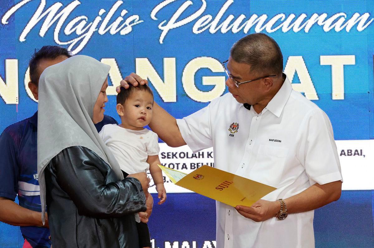 Menteri Dalam Negeri Datuk Seri Saifuddin Nasution Ismail (kanan) menyerahkan sijil kelahiran kepada penerima pada Majlis Peluncuran Kampung Angkat MADANI Kementerian Dalam Negeri di Kampung Pangkalan Abai hari ini- BERNAMA