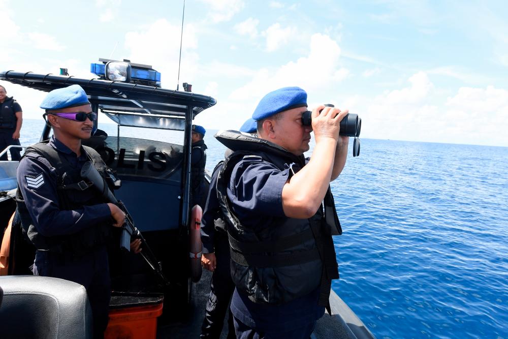 Sabah Marine Police commander Asst Comm Mohamad Pajeri Ali (R) uses a binoculars aboard the boat which is part of the earch and rescue (SAR) for six individuals including two children who were feared drowned after their boat sank in the waters of Merabung, Tungku. — Bernama