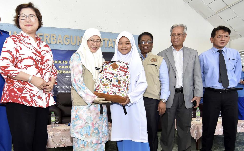 Deputy Prime Minister Datuk Seri Dr Wan Azizah Wan Ismail (2L) hand over school bag aid to students at the National Disaster Aid for fire victims in Putatan, on Feb 8, 2018. — Bernama