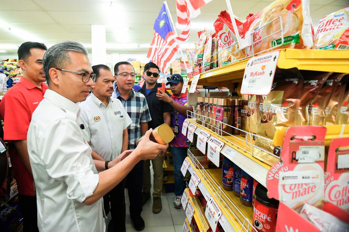 Menteri Komunikasi Datuk Fahmi Fadzil melihat harga barangan yang dijual pada harga Rahmah ketika meninjau penggunaan Sumbangan Asas Rahmah (SARA) di sebuah pasaraya di Merotai hari ini. Turut hadir Ketua Setiausaha Kementerian Komunikasi Datuk Seri Mohamad Fauzi Md Isa (dua, kiri). - BERNAMA