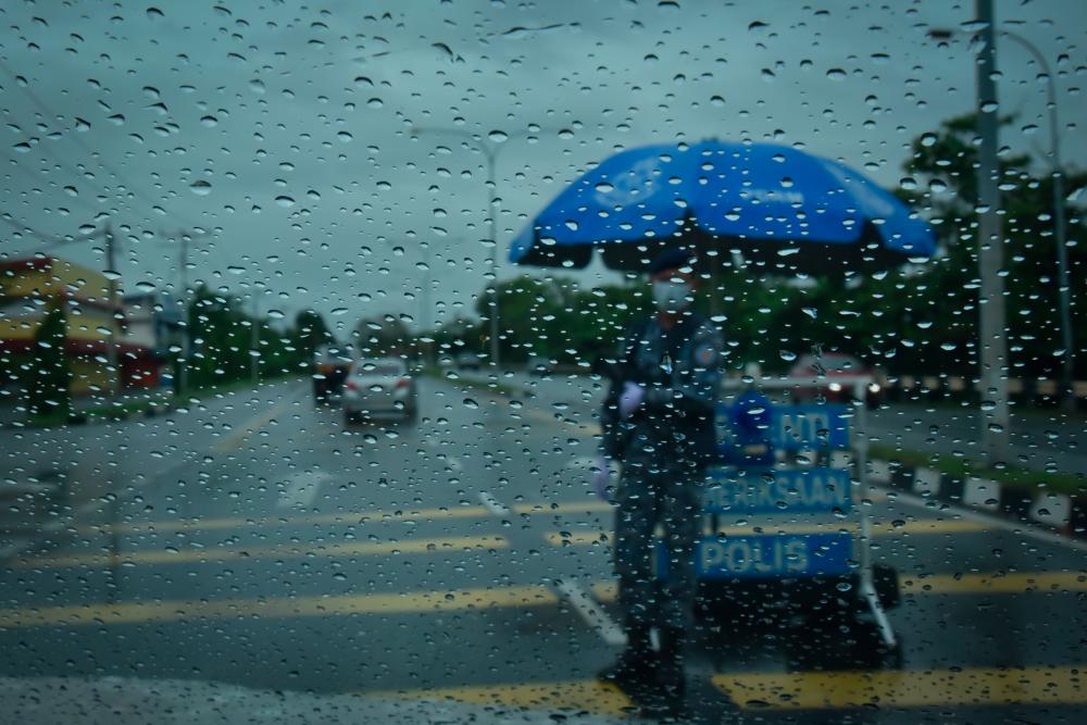 Frontliners still on duty at a roadblock despite the heavy downpour at Jalan Patau-patau in Labuan --fotoBERNAMA (2021) Copyrights Reserved