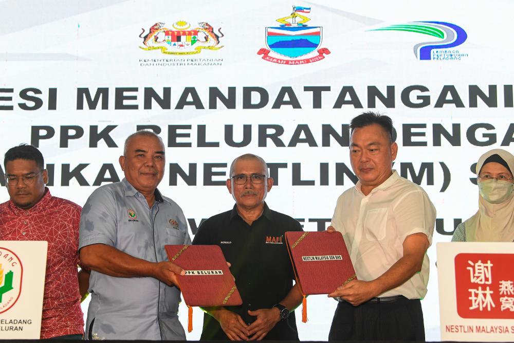 BELURAN, 15 Oct — Minister of Agriculture and Food Industry Datuk Seri Dr Ronald Kiandee (centre) watched as members of the Board of Directors of the Beluran Area Farmers Association, Arubani Mansur (second, left) and Duta Sialin Biotechnology Sdn Bhd Chief Executive Officer Datuk Sin Swee Seng (second, right) exchange memorandum of understanding documents after officiating the Beluran Swallow Festival today. BERNAMAPIX