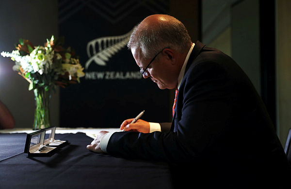 Australian Prime Minister’s Office shows Prime Minister Scott Morrison writing a message in a condolence book at the New Zealand High Commission in Canberra — AFP