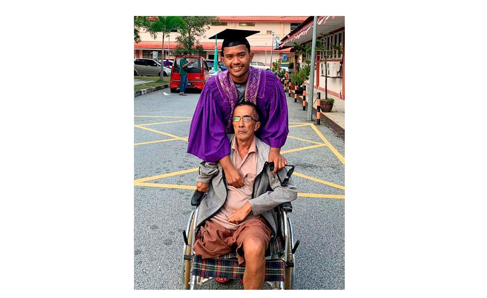 Muhammad Fahim Shamsuddin with his wheelchair-bound father Shamsuddin Md Amin, at the forensic unit of the Sultanah Nur Zahirah Hospital, on Nov 18, 2019. — Bernama