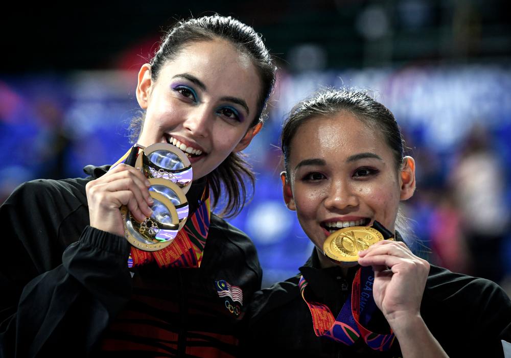 Artistic gymnastics athletes, Farah Ann Abdul Hadi (L) and Tracie Ang showing medals won respectively on the fourth day of the 30th SEA Games yesterday. — Bernama