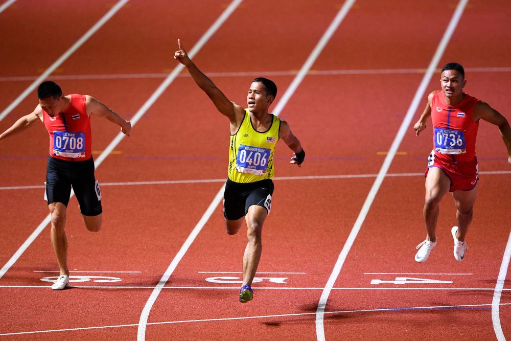 Muhammad Haiqal Hanafi (#0406) gestures as he races to the finish line to win in the men's 100m athletics event at the SEA Games in the athletics stadium in New Clark City, today. - AFP