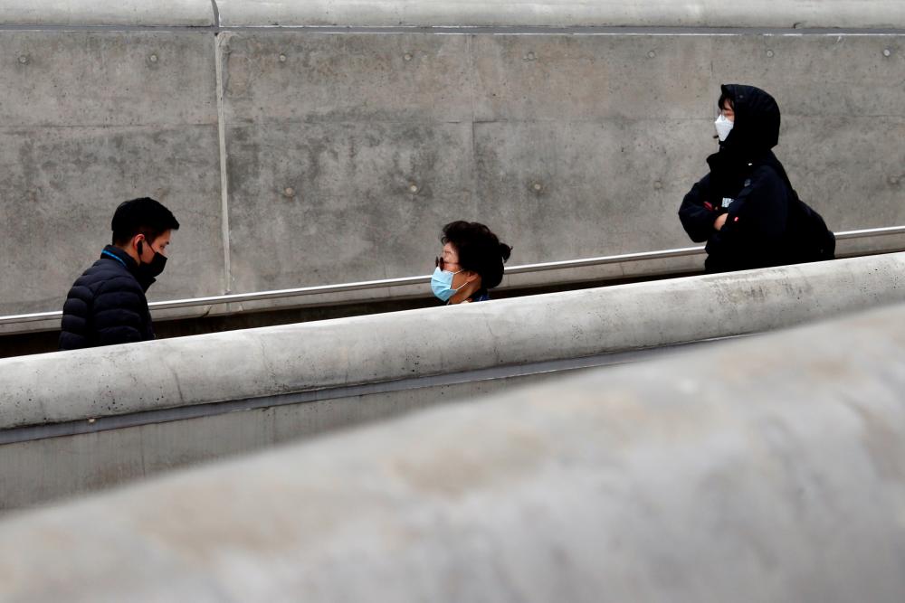 People wearing masks walk along a street amid the coronavirus disease (Covid-19) pandemic in Seoul, South Korea, November 20, 2020. — Reuters