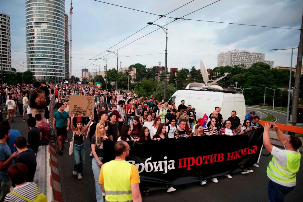 Protesters carry a banner, reading Serbia against violence, as they march over one of the main highway bridges during a rally to call for the resignation of top officials and curtailing violence in the media, a month and half after two back-to-back shootings that killed 18 people, in Belgrade on June 17, 2023. - AFPPIX