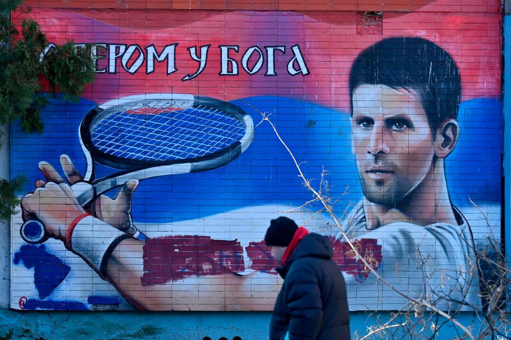 A local resident walks past a mural depicting Serbian tennis player Novak Djokovic in Belgrade on January 16, 2022. AFPPIX