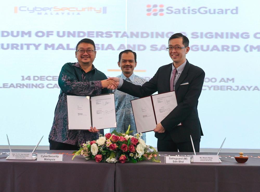 Mohamad Fauzi (centre) witnessing the exchange of documents between Amirudin (left) and Wang at the MoU signing ceremony. – Bernamapic