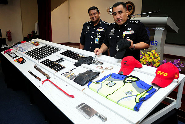 Selangor CID chief SAC Fadzil Ahmat (R) displays the material seized during the investigation of four people, who posed as police and immigration personnel during robberies, at a press conference at Selangor state contingent police headquarters, Shah Alam on April 19, 2019. — Bernama