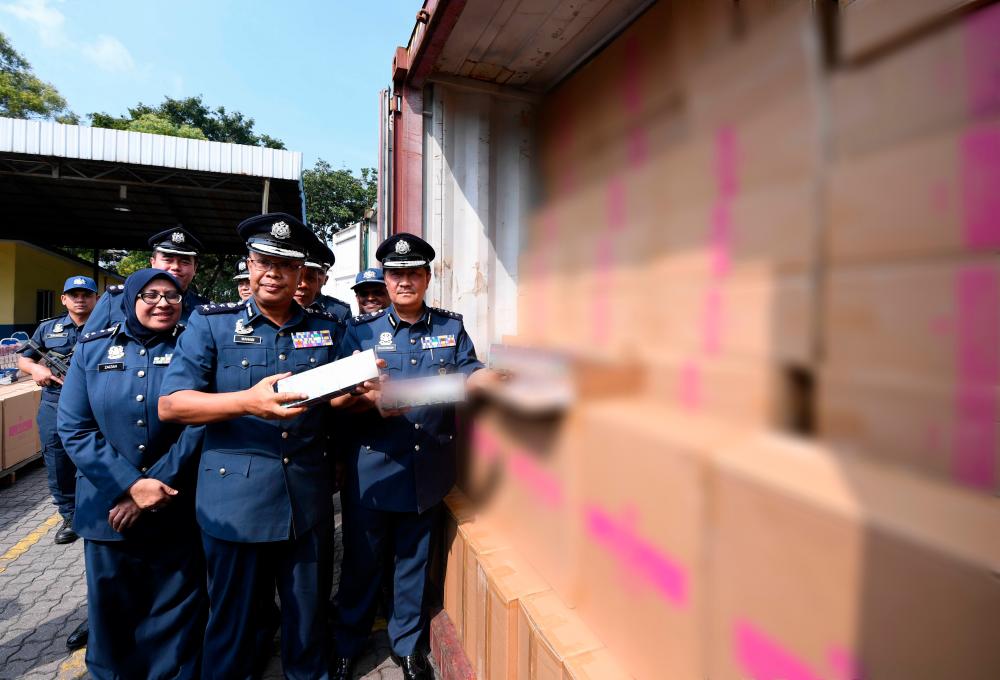 Central Zone Customs assistant director-general Datuk Zulkarnain Mohamed Yusuf (R) shows off some of the seized cigarettes during a press conference in Port Klang today. - Bernama