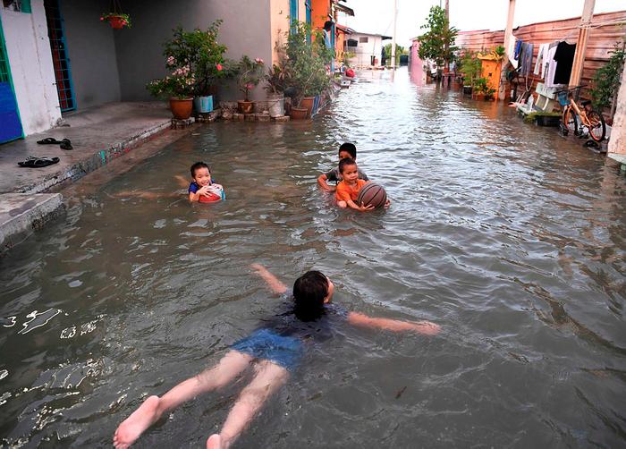 $!DOORSTEP POOL ... Children enjoying a splash right outside their home at the Bagan Hailam Village in Klang after the area as well as Kuala Selangor, Sepang and Sabak Bernam experienced a high-tide phenomenon yesterday. – BERNAMAPIX