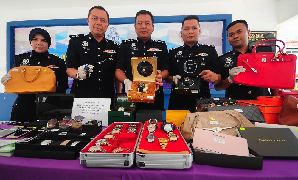 South Klang district police chief ACP Shamsul Amar Ramli (3rd from L) and other police personnel display the branded goods seized from an investment fraud syndicate known as ‘Jasman Investment’ at a media conference at the South Klang police headquarters on May 13, 2019. - Bernama