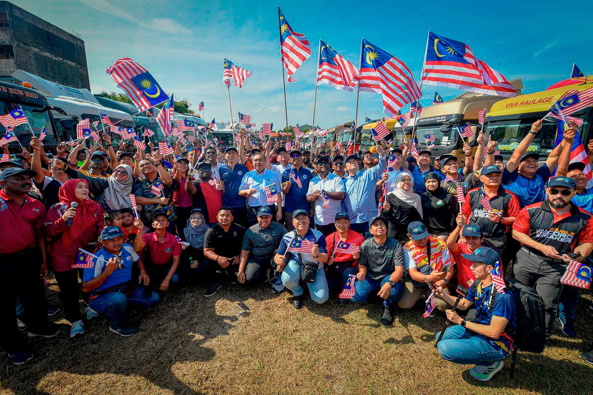Menteri Pengangkutan Anthony Loke (tengah) bergambar selepas menyerahkan Jalur Gemilang kepada 100 wakil pemandu haulier pada Program Kibarkan Jalur Gemilang Komuniti Pelabuhan Klang di Bangunan Kelab Sosial dan Rekreasi Lembaga Pelabuhan Klang (LPK), Pelabuhan Klang hari ini. - BERNAMA