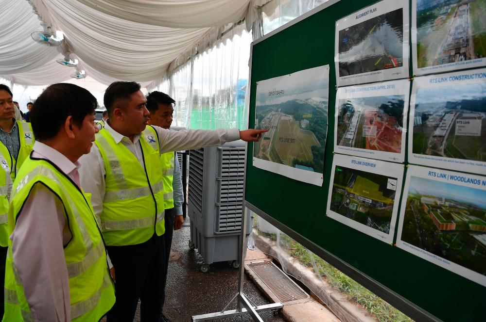 Transport Minister Anthony Loke Siew Fook and Singapore Transport Minister Khaw Boon Wan look at photos of the Rapid Transit System (RTS) construction during a visit to the proposed RTS Woodlands North site, Singapore on May 21, 2019. - Bernama
