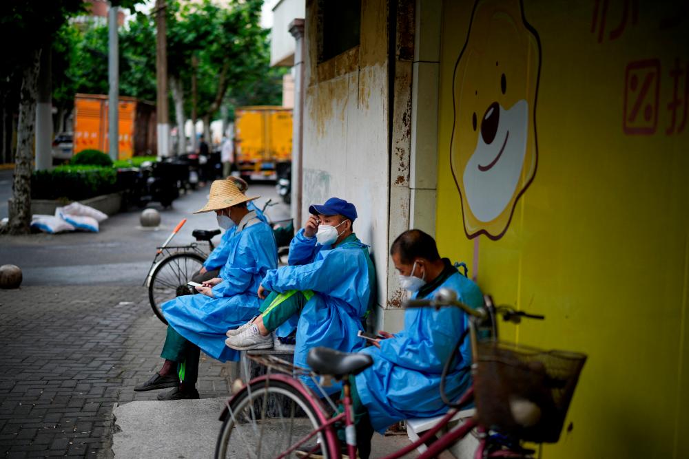 Workers in protective suits rest on a street during lockdown, amid the coronavirus disease (Covid-19) outbreak, in Shanghai, China, May 28, 2022. REUTERSpix