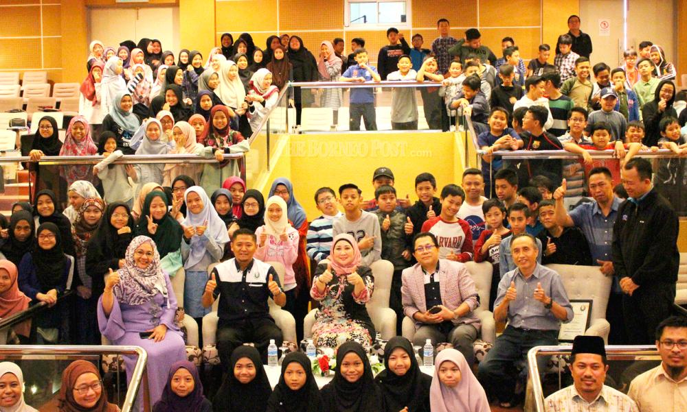 Sharifah Hasidah (seated centre) is seen with pupils and school officials.