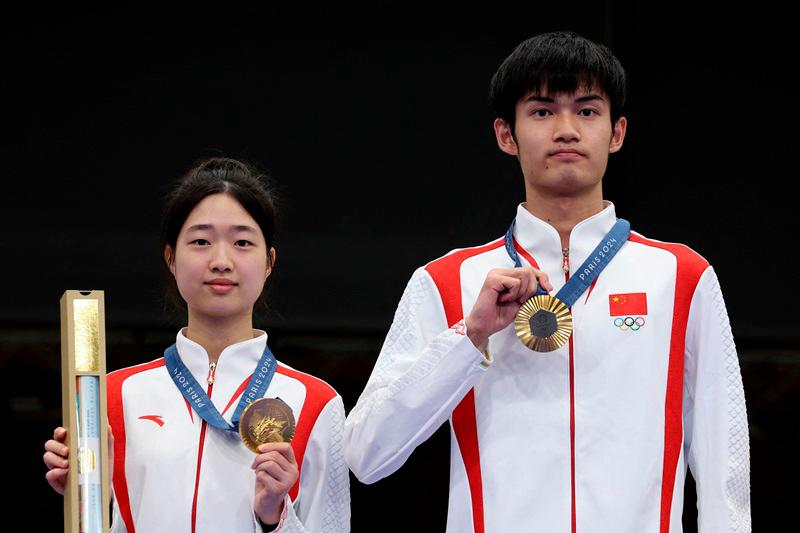 China's Huang Yuting and Sheng Lihao pose on the podium after winning the gold of the shooting 10m air rifle mixed team during the Paris 2024 Olympic Games at Chateauroux Shooting Centre on July 27, 2024. (Photo by ALAIN JOCARD / AFP)