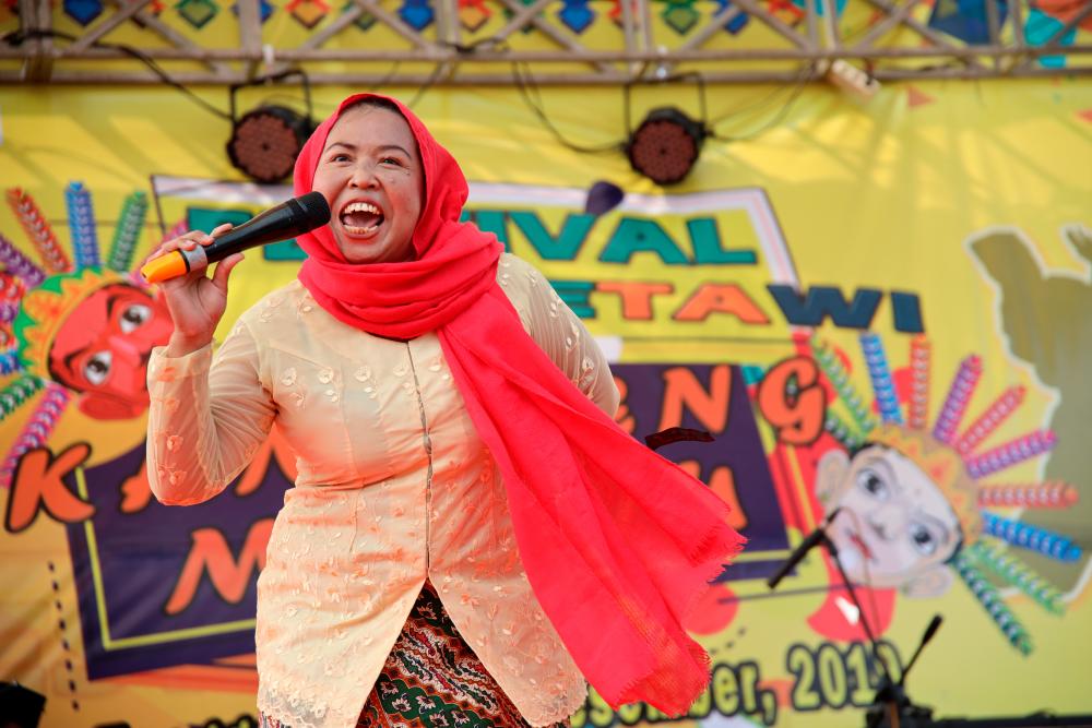 Sri Kusratih, 37-year-old vendor, reacts as she participates in a shouting competition at Betawi traditional festival in Jakarta, Indonesia December 14, 2019. - Reuters