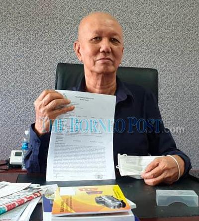 Sim Kim Hua shows the police report he lodged recently on the existence of the syndicate.-Borneo Post