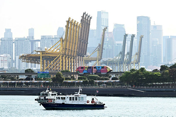 The giant sea port cranes of Tanjung Pagar container terminal and the high rise buildings of financial business district of Singapore is seen on March 14, 2019. — AFP