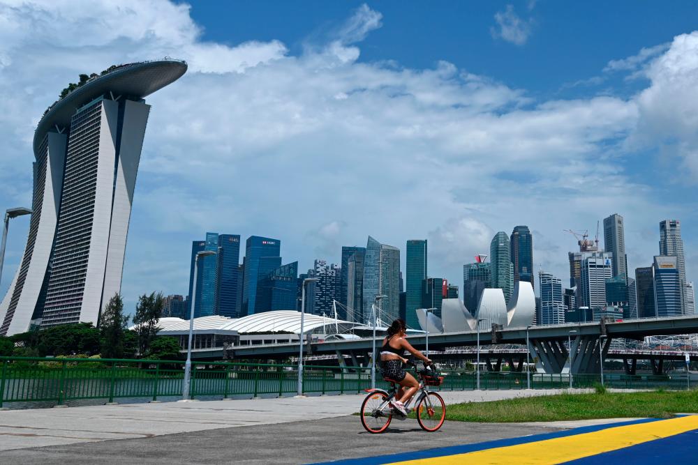A cyclist rides along the waterfront showing a general view of the financial business district in Singapore on May 26, 2020. Singapore's economy, a bellwether for global trade, could shrink by as much as 7.0 percent this year, the worst since independence, as the coronavirus pandemic throttles demand, the government said on May 26. — AFP