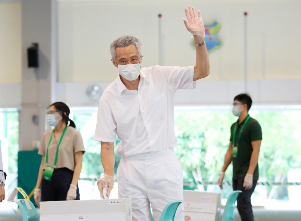 A handout photo released by Singapore's Ministry of Communications and Information (MCI) shows Singapore's Prime Minister Lee Hsien Loong (C) waving as he cast his vote at Alexandra Primary School during the general elections in Singapore, July 10, 2020. - EPA