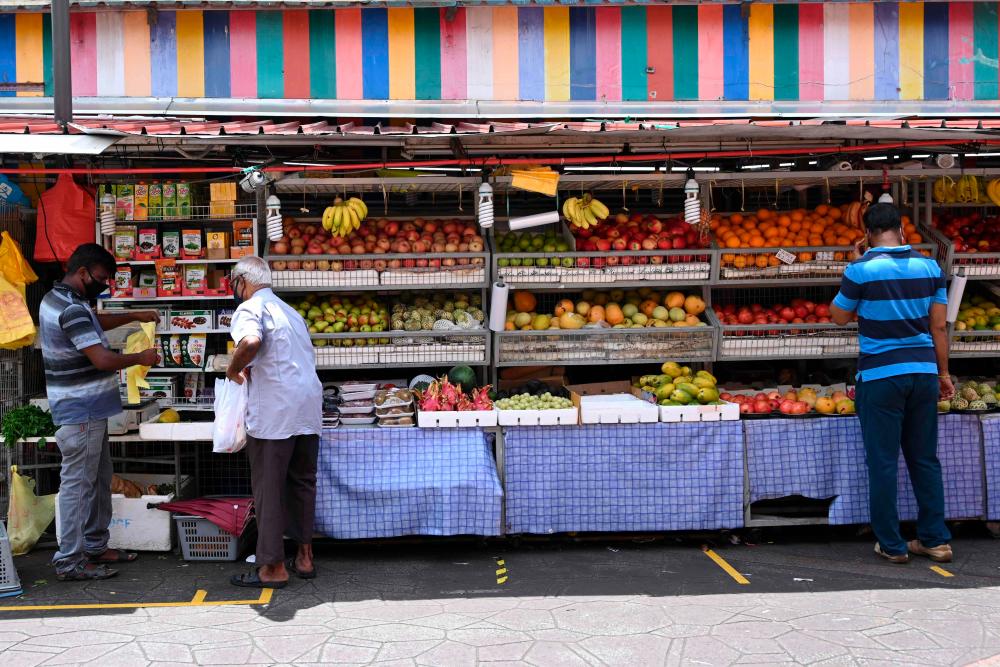 People wearing protective facemasks amid fears about the spread of the Covid-19 coronavirus visit a fruits stall in Singapore on May 8, 2020. - AFP