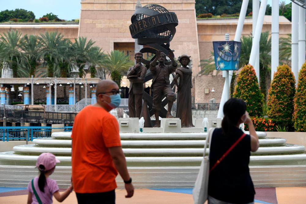Visitors walk in the Universal Studios Singapore theme park on the resort island of Sentosa in Singapore on July 3, 2020, as the attraction reopened after being temporarily closed due to concerns about the Covid-19 novel coronavirus. - AFP