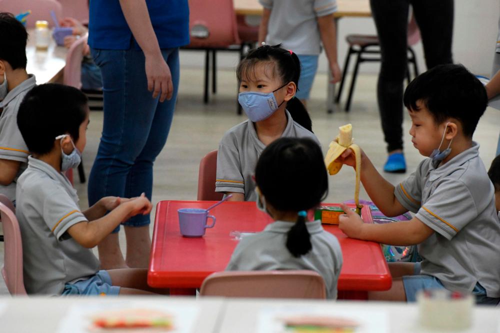 Pre-school children gather around a table inside their classroom as schools reopened in Singapore on June 2, 2020, as the city state eased its partial lockdown imposed to prevent the spread of Covid-19 in Singapore. — AFP