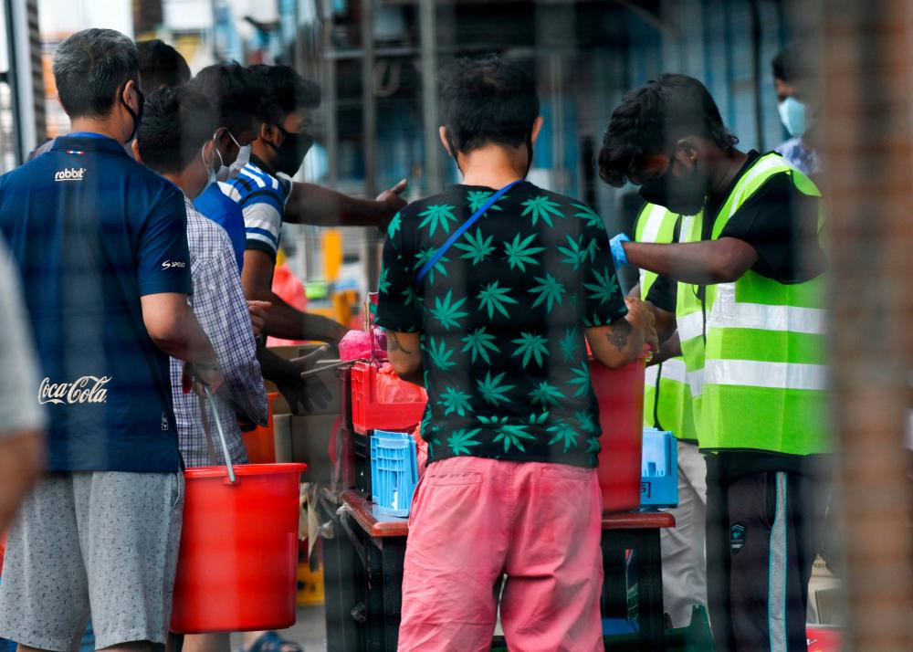 Residents queue for their food at Tuas South foreign workers dormitory that has been placed under government restriction as preventive measure against the spread of the COVID-19 coronavirus in Singapore on April 19, 2020. — AFP
