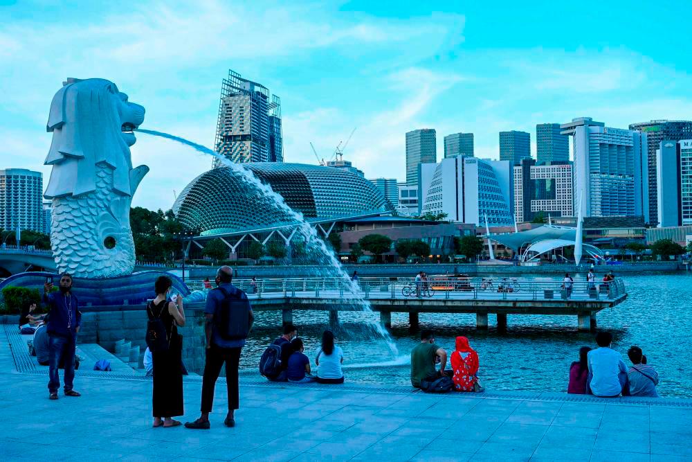 February 18, 2022, people relax along the waterfront next to the Merlion statue in Singapore. AFPPIX