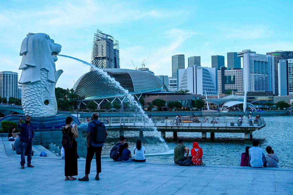 February 18, 2022, people relax along the waterfront next to the Merlion statue in Singapore. AFPPIX