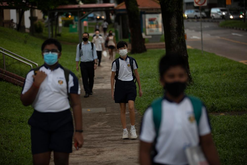 Students wearing protective face masks walk to attend school after they were reopened as part of the easing of coronavirus restrictions in Singapore, June 2, 2020. - EPA