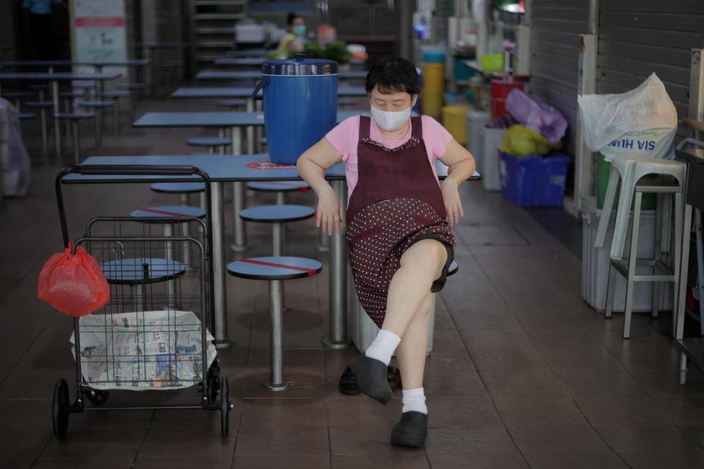 A hawker wearing a face mask rests in a food centre in Singapore, 28 May 2020. - EPA