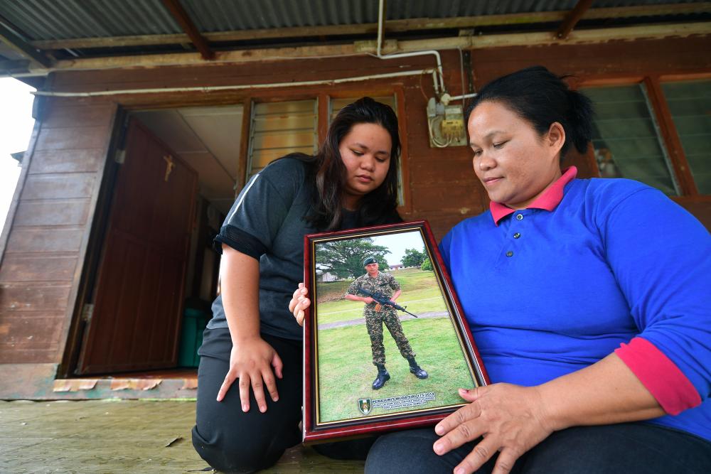 Kimkee Jiwa, 50, (R) pointed to the photograph of his nephew L/Cpl Moses Logers, 25, who was reported missing while on duty in Pulau Perak since Friday, when met by Bernama at her residence in Kampung Senibong, Bau near here today. - Bernama