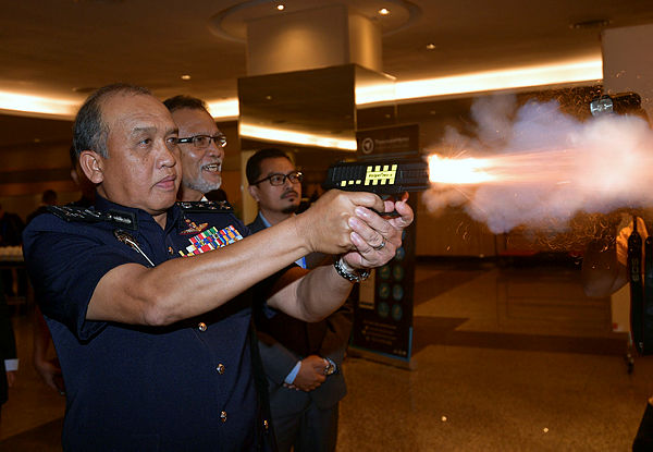 Bukit Aman Crime Prevention and Community Safety Department (JPJKK) director Datuk Seri Rosli Ab Rahman tests a taser gun after officiating the the 31st Malaysian Auxiliary Police Association yesterday — Bernama