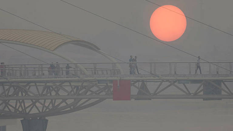 A view of a reddish-looking sun due to the haze, at the Darul Hana Bridge in Kuching yesterday. — Bernama