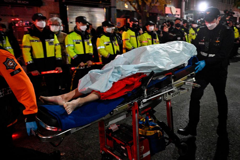 The body of a victim of a Halloween stampede, which left more than 140 people dead, is carried on a stretcher in the neighbourhood of Itaewon in Seoul/AFPPix