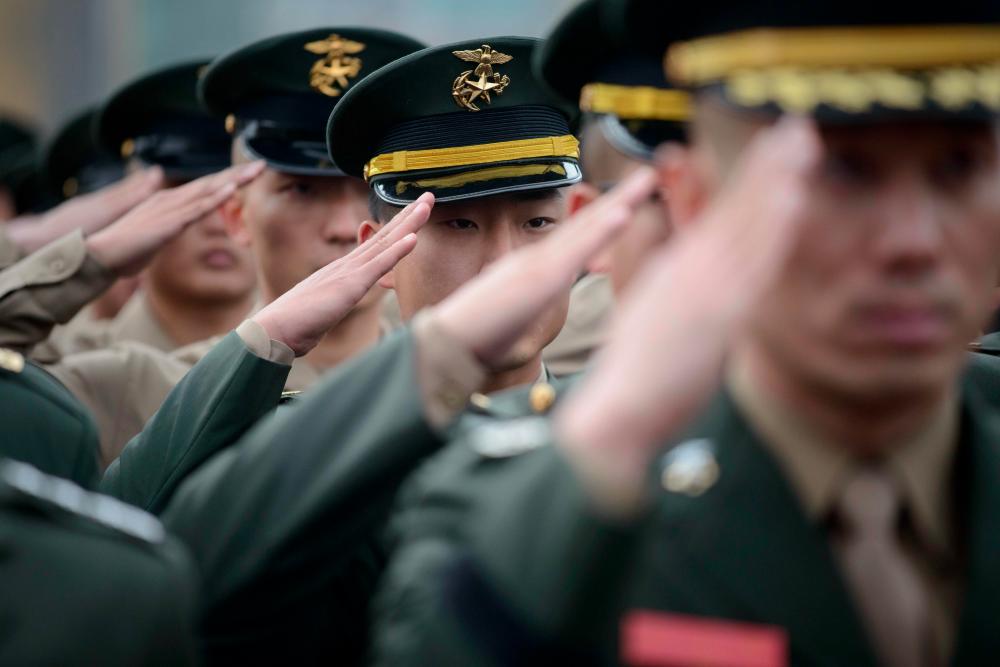 In a photo taken on Nov 23, 2014, South Korean soldiers salute as they attend a fourth anniversary event marking the bombing of Yeongpyeong island by North Korea in 2010. — AFP