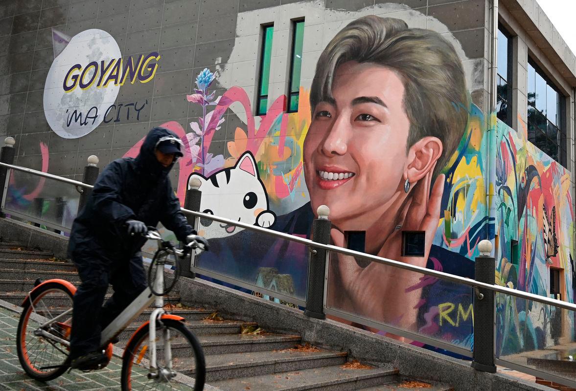 A man cycles past a mural depicting RM, a member of K-pop group BTS, in Goyang, northwest of Seoul, on December 11, 2023 - AFPPIX