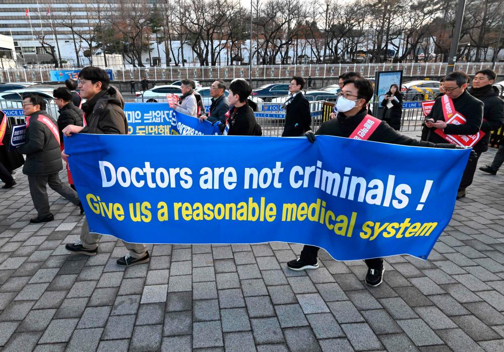 Doctors carry a banner reading “Doctors are not criminals!” as they march toward the Presidential Office during a rally to protest against the government’s plan to raise the annual enrolment quota at medical schools, in Seoul on February 25, 2024/AFPPix