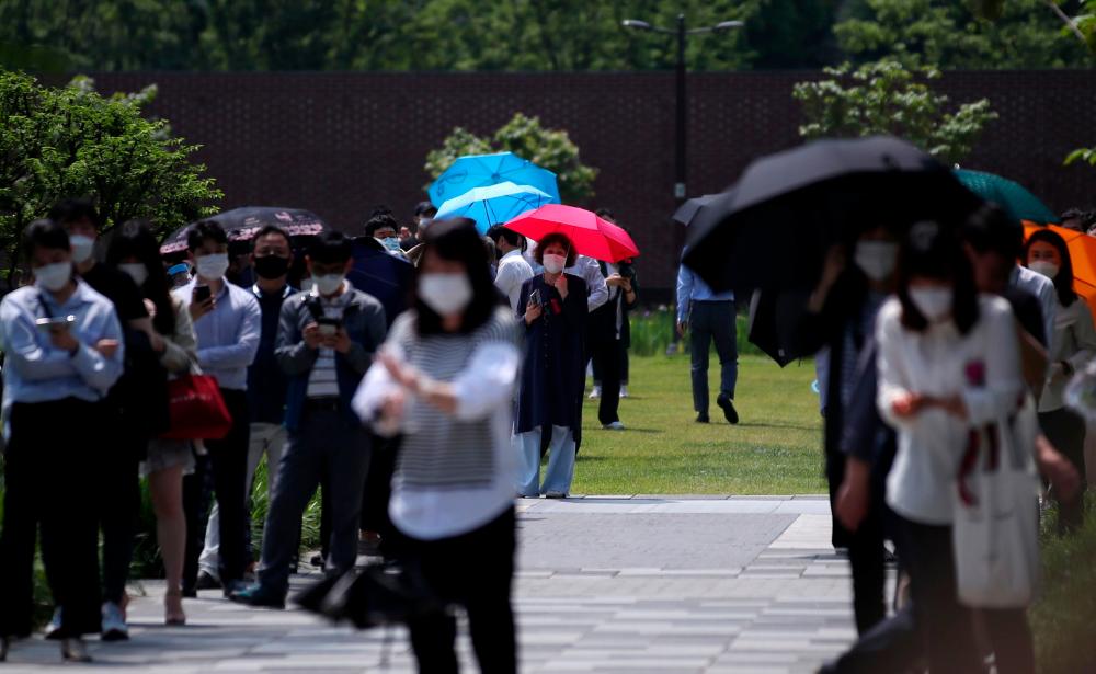 Visitors wearing face masks wait in line for the Covid-19 coronavirus test at a temporary virus testing centre in Seoul on May 29, 2020. — AFP