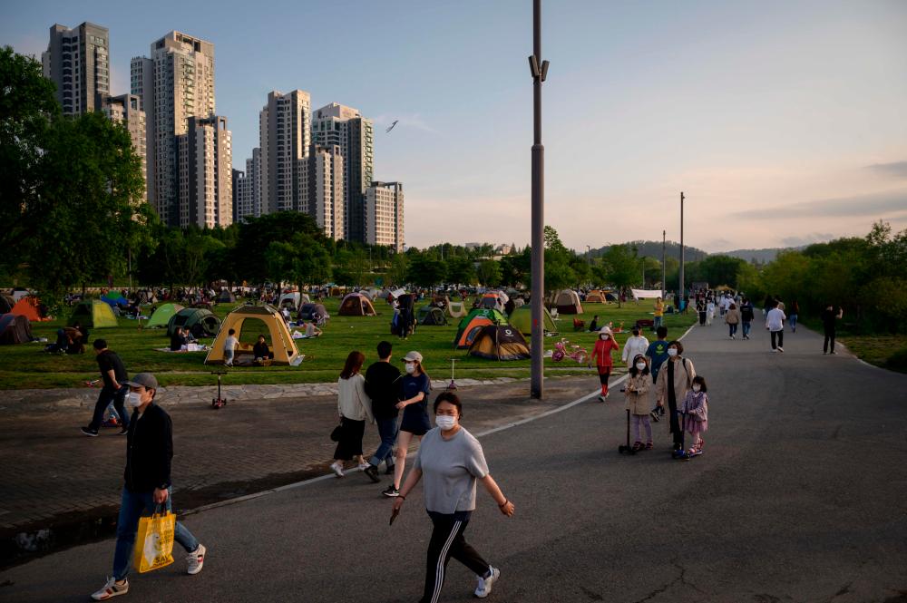 In a photo taken on May 24, 2020 people wearing face masks amid concerns of the Covid-19 novel coronavirus walk through a park in Seoul. — AFP